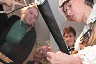 Musical, Ausstellung, Holzskulpturen: Wie Eibenstock versucht, seiner Wohltäterin ein Gesicht zu geben - Regine Unger (r.) aus Eibenstock ist zur Eröffnung der Ausstellung zu Clara Angermann im Schatzhaus Eibenstock in die Rolle von Clara Angermann geschlüpft und hat das Tambourieren demonstriert.