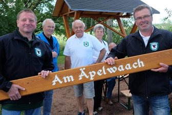 Musik an jeder Bank - Vereinschef Ingo Claus (rechts) hat mit Christian Meyer (links) das Schild für den Rastplatz "Am Äpelwaach" angebracht. Wolfgang Winkler (3. v. l.) und Klaus Böhm (2. v. l.) haben sich um die mit Musik der Oelsnitzer Blasmusikanten hinterlegten QR-Codes gekümmert. 