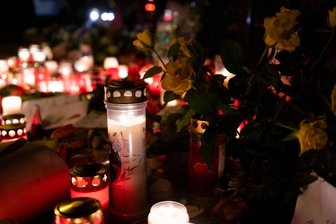 Mutter und Kind nach Anschlag in München gestorben: Familie wendet sich an Öffentlichkeit - Blumen und Kerzen stehen auf dem Bürgersteig in der Nähe der Stelle in München, wo am 13.02.2025 ein Auto in eine Gruppe von Demonstranten gefahren war. Zwei Tage nach dem Anschlag sind ein zweijähriges Kind und eine 37 Jahre alte Frau an ihren Verletzungen gestorben.