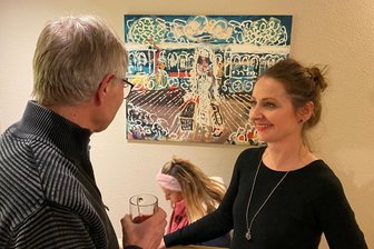 Mylauer stürmen Mylauer Kosmetikstudio: Was da plötzlich die Kasse klingeln ließ - Augenblicke eines bezaubernden Abends. Kosmetikerin und Kurzzeit-Kuratorin Bianca Bräutigam im Gespräch mit Josef Wetzl, dem Sohn von Maler Josef Wetzl. Im Hintergrund das Wetzl-Bild „Ankunft im Kurbad“.