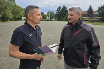 Nach Aus für Übungsplatz in Steinpleis: Fraureuth rettet Fahrschule mit Angebot für Ausweichfläche - Hauptamtsleiter Robby Safferthal (l.) schaut sich mit dem Leiter der Erich-Glowatzky-Mehrzweckhalle, Jens Gläser, den angrenzenden Platz an. Den darf künftig die Fahrschule Röder nutzen.