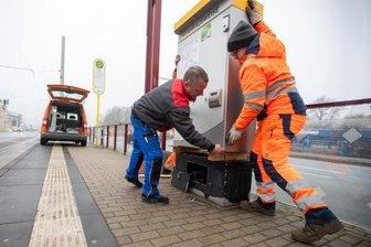 Nach Automatensprengung: An der Haltestelle Bahnhof Mitte gibt’s jetzt wieder Straßenbahntickets zu kaufen - Drei starke Männer braucht’s, um den 300-Kilo-Automaten in die Verankerung zu setzen.