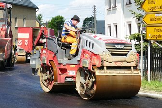 Nach B 174-Sperrung: Wie schnell die Transit-Schäden auf den Umleitungsstrecken im Erzgebirge behoben werden - In Börnichen wird auf der Straße, die während der Sperrung der B 174 als Umleitung diente, ein Stück Fahrbahn erneuert.