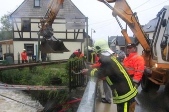 Nach der Flut beginnt das Aufräumen - In Bockau wurde am Kapellenbach eine Gasleitung destabilisiert. Feuerwehrleute befestigten sie vorerst an einem Stahlträger.