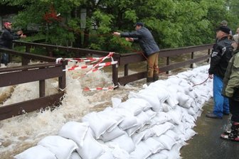 Nach der Flut: Diskussion über den geplanten Abriss der Fußgängerbrücke - Gefahr im Verzug: An der Brücke staute sich das Pöhlwasser, flutete die Straße und suchte seinen Weg auf die angrenzenden Grundstücke. Sandsäcke sollten das verhindern. In der Nacht waren die Felder aus dem Brückengeländer herausgesägt worden, am Tag wurde das Geländer ganz entfernt.