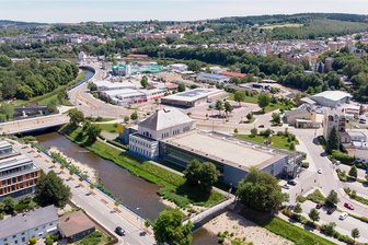 Nach Erdwärme-Flop: Wie will Plauen das Stadtbad beheizen? - Wie ein Schiff liegt das Stadtbad am Ufer der Weißen Elster: links der wie die Brücke ragende Altbau, daneben der 2005 in Betrieb genommene Neubau. Rechts daneben, auf dem Parkplatz, soll ein Anbau entstehen.