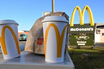 Nach Gerichtsurteil: Kommt im Erzgebirge jetzt die Verpackungssteuer auf Einwegmüll? - Eine McDonald's To-go-Tüte und ein To-go-Becher stehen vor einer der Filialen. Das Bundesverfassungsgericht hat kürzlich entschieden, dass Kommunen eine Verpackungssteuer auf Einwegbecher und Essensverpackungen erheben dürfen.