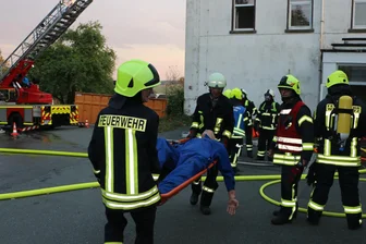 Nach länderübergreifender Feuerwehrübung in alter Reuther Schule wird diese abgerissen - Einer der Vermissten aus dem Haus wird auf der Trage liegend geborgen.
