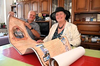 Nach sechs Wochen im Koma: Kulturchefin von Hainichen kämpft sich zurück ins Leben - Evelyn Geisler mit ihrem Mann Uwe zuhause in Hainichen. Die Mitarbeiter des Rathauses haben ihr diese acht Meter lange Rolle mit Versen und Bildern geschenkt.