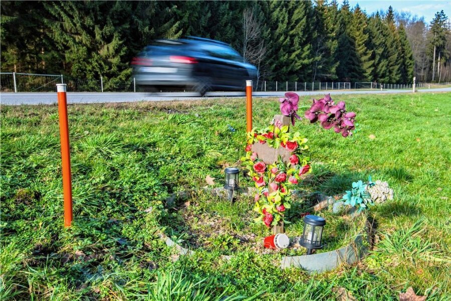 Nach Unfall mit drei Toten im Erzgebirge: Tesla-Fahrerin schweigt vor Gericht - Trauer an der Unfallstelle: Ein Gedenkkreuz erinnert seit mehr als zwei Jahren an die drei getöteten Frauen. Auch am Tag des Prozessauftakts war das Kreuz mit Kunstblumen geschmückt. 