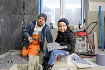 Nach Unwetter im Juni: Haus von Familie in Meerane auch an Weihnachten eine Baustelle - Das Bad ist noch eine Baustelle: Der sechsjährige Tyler reicht Papa Benjamin Gottschling die Fliesen.