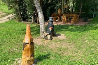 Nach Vandalismus im „Karzl-Eck“ in Auerbach: Ein neues Karzl muss her - Figuren und Sitzgruppe stehen wieder, vorn das helle Wurzelmännlein, dahinter das schwarze Karzl, dieses allerdings mit sichtbarem Schaden am Hut.