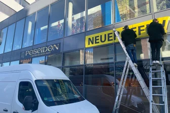 Nach Vapiano-Aus in Chemnitz: Nachfolger zeigt erste Zeichen - Zwei Männer haben das neue Firmenschild und ein Plakat mit der Aufschrift „Neueröffnung“ angebracht.