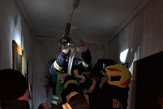 Nach Wasserrohrbruch in Rochlitz: Großvermieter am Rotieren - Ein Feuerwehrmann schüttet in Rochlitz aus dem Lampenschirm Wasser in einen Eimer.