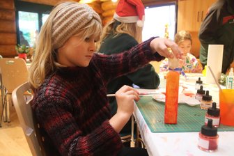 Nachhaltiges Weihnachten im Augustusburger Forst - Die neunjährige Eva Maria malte bei der Bastelstation auf der Augustusburger Wildweihnacht eine Kerze aus Holz an.