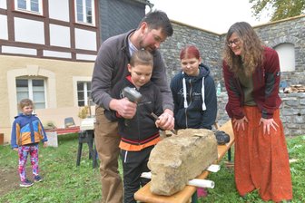 Nassau handwerkt wenige Tage vor allen anderen im Erzgebirge: Ein cleverer Schachzug? - Erlebnispfarre Nassau: Steinmetz Lukas Hänisch zeigt Nico und Michelle das richtige Bearbeiten eines Sandsteines. Hilke Domsch (r.) schaut zu.