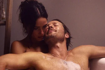 Neu im Kino: „A Killer Romance“ mit Glen Powell als neuer Hollywood-Star - Adria Arjona (links) als Madison Masters und Glen Powell als Gary Johnson in einer sexy Szene des Kinofilms „A Killer Romance“. Doch beide treiben ein falsches Spiel ...
