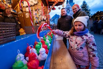 Neue Angebote auf dem Plauener Weihnachtsmarkt: Was Besucher in diesem Jahr nicht verpassen sollten - Beim Entenangeln am Stand von Jessica Sehning ist die sechsjährige Lotte mit voller Konzentration dabei. Ihre Mutter Melanie Glaß schaut mit Lebensgefährte Markus Wunderlich zu.