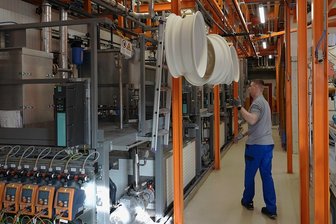 Neue Anlage für Pulverbeschichtung geht in Reinsdorfer Lebenshilfewerkstatt in Betrieb - Mitarbeiter Ronny Steuer mit Felgen inmitten der neuen Pulverbeschichtungsanlage. An Führungsschienen werden die Teile durch die Anlage transportiert. 