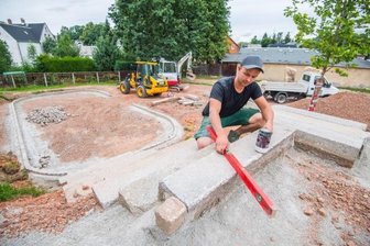 Neue Hangrutsche für mehr Spielplatz-Spaß - Nachdem es im Vorjahr den Auftakt zur Sanierung des Spielplatzes an der Jahnstraße in Neukirchen gegeben hat, wird jetzt weiter gebaut. Landschaftsgärtner Vincent Einenkel beim Setzen des Aufstiegs zur Hangrutsche und zum Grillplatz.
