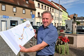 Neue Hoffnung für alte Schandflecke: Lunzenau setzt nach Abriss wieder auf Stadtsanierung - Bürgermeister Ronny Hofmann auf dem Markt in Lunzenau mit dem Plan des Stadtsanierungsgebietes. In den nächsten zehn Jahen sollen viele Fassaden in der Stadt erneuert werden.
