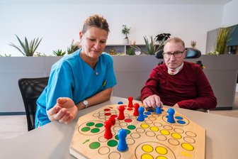 Neue Intensivpflege-WG im Erzgebirge: Wie sich ein Bäcker zurück ins Leben kämpft - Holger Dollase spielt mit Pflegefachkraft Jana Busch Mensch-ärgere-Dich-nicht. Der Bäcker wohnt in der neuen Intensivpflege-WG in Stollberg. Nach einem Schlaganfall freut er sich über Fortschritte.