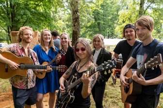 Neue Kunstwerke - von Musik inspiriert - Während die Holzbildhauer ihre Kunstwerke aus Baumstämmen herausarbeiten, erschaffen die Teilnehmer des Singer-Songwriter-Sommercamps um Leiterin Anika Jankowski (3. v. l.) neue Songs. 