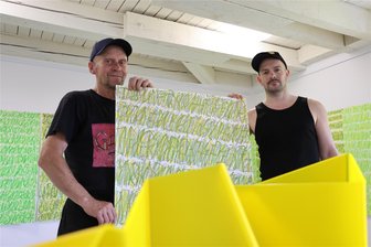 Neue Schriften und Buttermilch - Künstler setzt bei Ausstellung im Erzgebirge auf besondere Techniken - Frank Maibier (l.) und Thomas Feldberg bauen zusammen die Ausstellung in der Galerie in Meinersdorf auf.