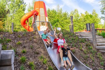 Neuer 1,7-Millionen-Euro-Spielplatz im Erzgebirge im Selbsttest: Lohnt sich der Besuch? - Ab auf die Rutsche: Paul, Marie, Lara (v. l.) und Lukas Lässig (vorne) machen den Selbsttest auf dem neuen Spielplatz in Bad Schlema. Auch mit dabei: Papa Thomas und Oma Eva.