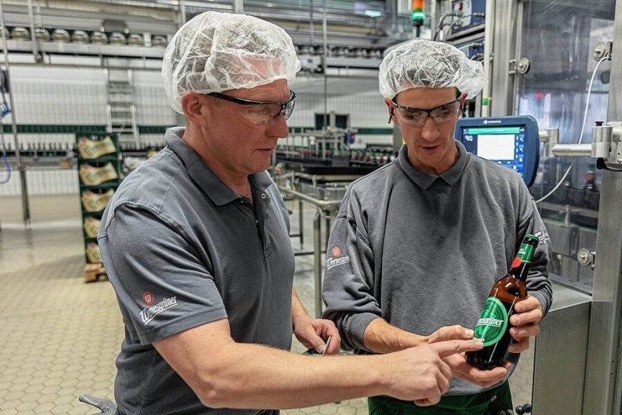 Neuer Auftritt für Wernesgrüner: Brauerei modernisiert Design - Alles im grünen Bereich? Brauereidirektor Marc Kusche und Anlagenführer Tony Voigt (rechts) kontrollieren, ob die neuen Etiketten korrekt auf den Flaschen sitzen, wenn sie Abfüll- und Etikettieranlage durchlaufen haben.