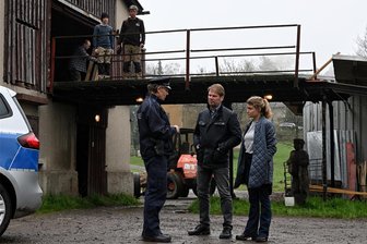 Neuer Erzgebirgskrimi: Was unter den Erzgebirgern für Diskussionen sorgen wird - Hauptkommissar Robert Winkler (Kai Scheve, Mitte) und seine Kollegin Karina Szabo (Lara Mandoki) besuchen das Grundstück der Familie Ott, wo Polizeihauptmeister Wagner (Thomas Bading) die Suche nach der verschwundenen Tochter Mia eingeleitet hat. Im Hintergrund ganz links am Eingang: Komparse Robby Schubert aus Gelenau.