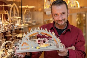 Neuer Vogtland-Schwibbogen mit Schanze und Marienquelle - Der neue Vogtland-Schwibbogen mit LED-Lichtband aus der Drechslerei Kuhnert Rothenkirchen, den VerkäuferRobert Arnold präsentiert, leuchtet wahlweise mit Netzstrom oder Powerbank.