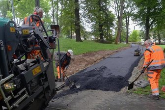 Neuer Weg durch den Auerbacher Stadtpark - Am Freitag baute ein Team der Firma UTR die Schwarzdecke in den neuen Weg im Stadtpark ein. Am Montag soll die Strecke für Fußgänger, Radler und Rollstuhlfahrer freigegeben werden.