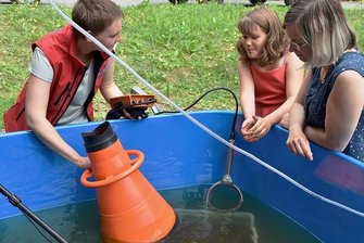Neues Außenbecken für Muschelaufzucht im oberen Vogtland - Luisa Kauert (links) von der TU Dresden erklärt Franziska Pohl und ihrer Tochter Lene aus Auerbach, wie die Muschelaufzucht funktioniert. Mit einem neuen Außenbecken verbessern sich dafür die Bedingungen.