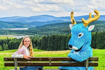 Neues Maskottchen fürs Bürgerfest in Stützengrün: Blauer Hirsch an der "Route 169" im Erzgebirge gesichtet - Gestatten, das ist Routi, das neue Maskottchen des Bürgerfestes "Route 169" in Stützengrün. Er sitzt neben seiner Schöpferin Eileen Leistner (13), die sich Routi vor vier Jahren ausgedacht hat.