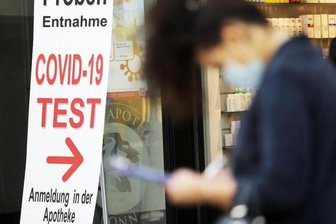Eine Frau füllt vor einer Apotheke in Bonn ein Formular für einen Covid-19-Test aus.