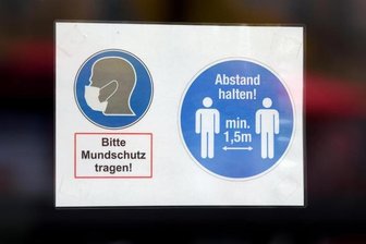 An der Tür eines Geschäfts weist ein Schild auf die geltenden Corona-Regeln hin.