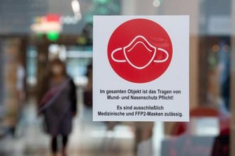 Ein Schild am Eingang zu einer Einkaufspassage weist auf das Tragen von Mund- und Nasenschutz hin.