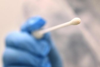            Ein Arzt hält in einer Hausarztpraxis einen Tupfer für einen Coronatest-Abstrich.