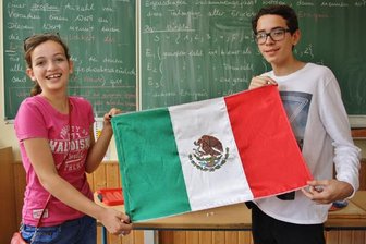Niederwiesaer feiern Jubiläum und bekommen Besuch aus Mexiko - Anna Biro (l.) und Rodrigo Sumohano zeigen in einem Klassenzimmer der Oberschule Niederwiesa die mexikanische Flagge.