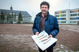 "Noch ein drittes Jahr geht das nicht" - Die Pläne sind fertig: Bürgermeister Raik Schubert auf dem Hartplatz in Niederwiesa. Dort soll ab März die neue Zweifeldhalle entstehen. Im Hintergrund links die Oberschule, rechts die Grundschule. 