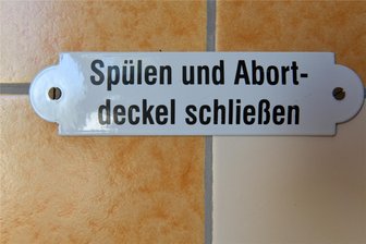 Nützlich und originell zugleich: Diese Toiletten in Mittelsachsen sind einen Besuch wert - Ein Hinweisschild in den historisch angehauchten Toilettenanlagen in der Friedrich-August-Schmiede in Großschirma. Wer es nicht weiß: Früher wurden Klos auch als Abort bezeichnet.