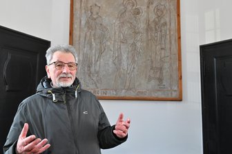 „Nur nichts wegschmeißen, lieber mir geben“: Wie ein Erzgebirger die Geschichte seiner Heimatstadt bewahrt - Heinz Poller vor dem Putzritzbild in der Auer Friedenskirche. Als Ortschronist bietet er Führungen durch die Kirche an, die er als Mitglied der Kirchgemeinde wie seine Westentasche kennt.