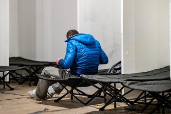Obdachlosigkeit verschwindet nicht, nur weil man sie nicht sieht - Ein Wohnungsloser macht sich in einer Notunterkunft auf einem Feldbett bereit für die Nacht.