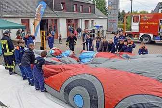Oederan: Gäste der Feuerwehr meistern Selbstversuch mit hydraulischer Schere und Spreizer - Alle Hände der Jugendfeuerwehrleute wurden gebraucht, um die Hüpfburg in Form eines Feuerwehrautos aufzubauen.