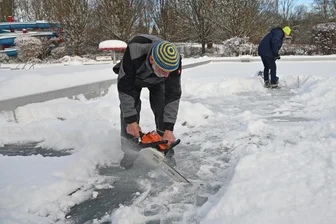Oederaner Winterschwimmer: Blau-gelbe Eishaie bereiten Eisbaden bei Nacht vor - Detlef Fröbel knackt den Eispanzer im Stadtbad mit einer Kettensäge.