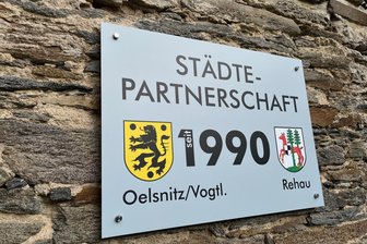 Oelsnitz und Rehau feiern am Sonntag Jubiläum - Im Innenhof des Oelsnitzer Rathaus weist eine Tafel auf die Partnerschaft mit Rehau hin.