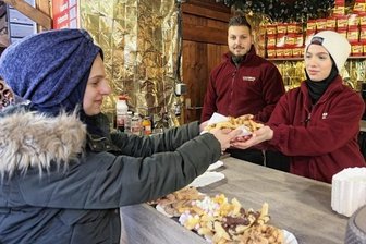 Olé: Churros erobern Zwickauer Weihnachtsmarkt - Hmmm, lecker: Esraa Alferekh (rechts) reicht Rayan Bitar am Stand von Ahmad Kiwan (Mitte) eine Portion frisch gebackene Churros.