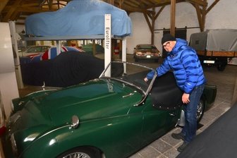 Oldtimer finden neuen Platz - Michael Lienemann mit seinem Triumph TR 3. Wie dahinter zu sehen, kann per Hebebühne auch ein Auto über dem anderen parken. Theoretisch würden sogar drei Fahrzeuge übereinander passen: Die Halle ist acht Meter hoch.
