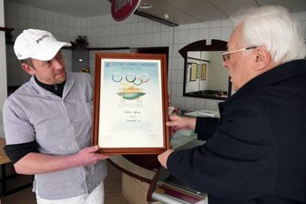 Olympia in Cortina D’Ampezzo: Schon vor 70 Jahren ging diese Erzgebirgerin für Deutschland in die Loipe - In seiner Fleischerei präsentiert Jörg Spiegelhauer (links) dem Hobby-Historiker Joachim Zacher das Olympia-Diplom, das seine Großmutter Elfriede Uhlig 1956 in Cortina erhielt.
